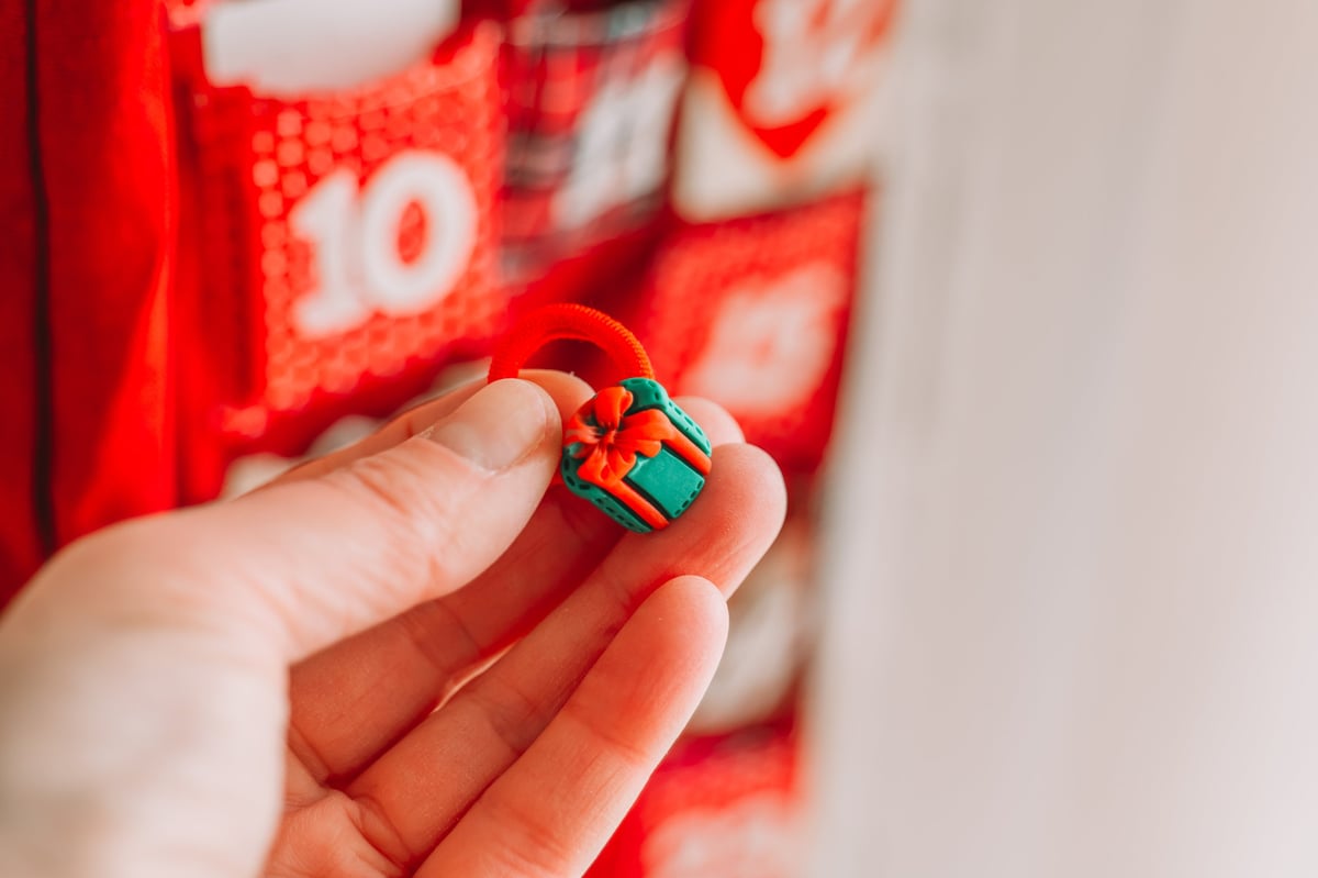 Hand holding a wrapped Christmas advent calendar gift in a cozy festive setting